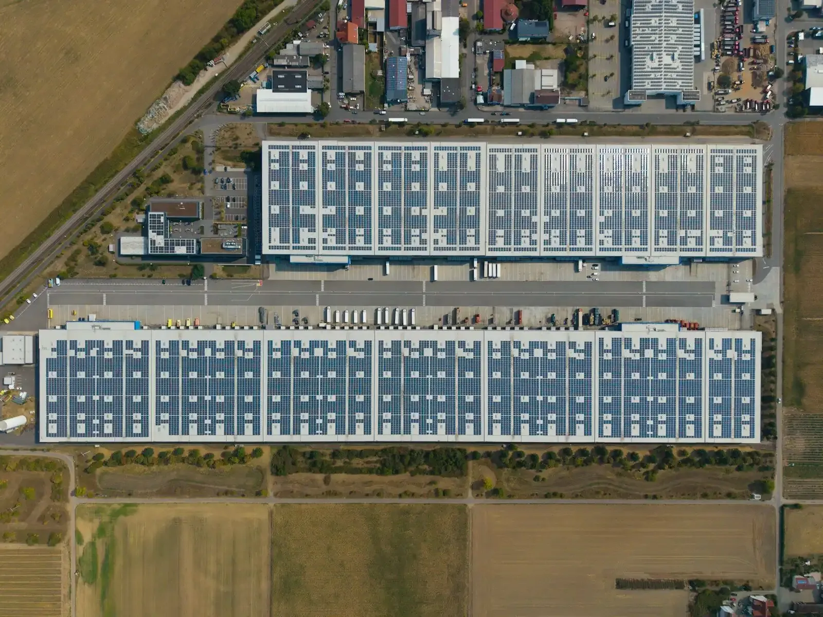 Deux grands entrepôts dont les toitures sont couvertes de panneaux solaires, vus du ciel